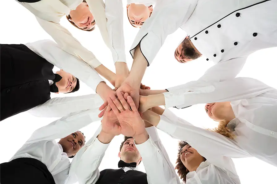 Restaurant service and culinary team with hands joined together in unity